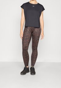 Sort kortærmet skjorte, kombineret med brune leggings med leopardprint. Bruges sammen med sorte sportssko. Enkel design, glat tekstur.