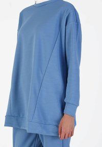 Light blue oversized sweatshirt made of soft fabric, featuring a round neckline, long sleeves, and a straight hem with side seams.