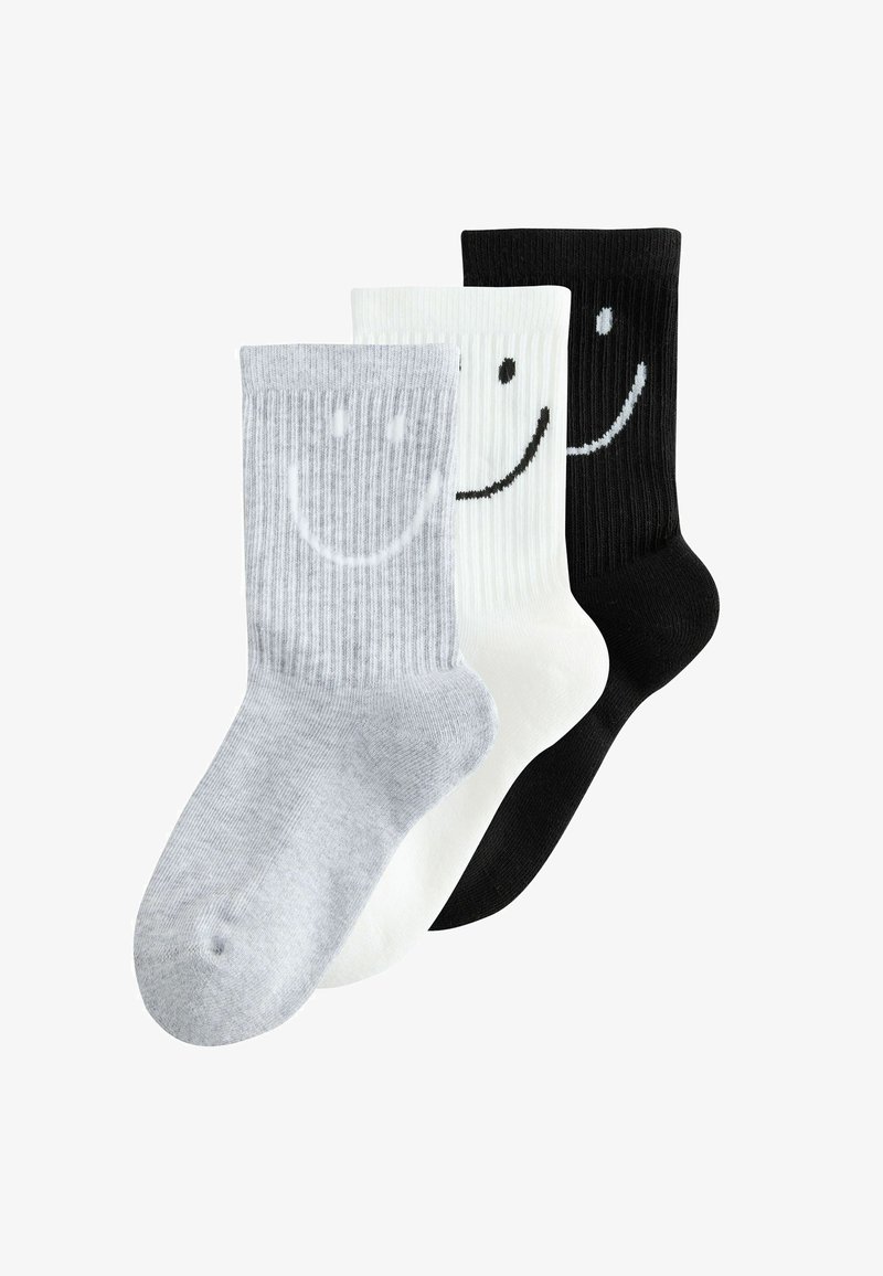 Trois paires de chaussettes côtelées en gris, blanc et noir, chacune ornée d'un grand visage souriant près du revers.