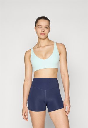Lyseblå sports-bh med V-hals-design, parret med højtaljede marineblå shorts med kontrastsyet detaljer. Glat stofstruktur.