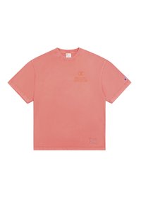 Camiseta de algodón rosa con mangas cortas, cuello redondo y una impresión de logo. Los acentos notables incluyen un parche en la parte inferior izquierda.
