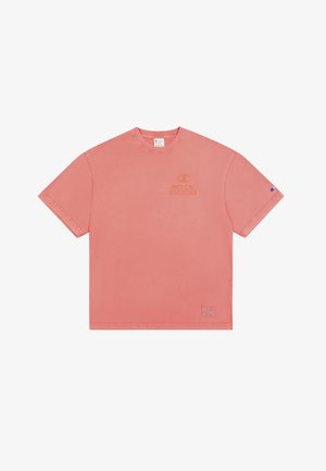 T-shirt in cotone rosa con maniche corte, collo a giro, e stampa del logo. Accenti notevoli includono una toppa sul lato sinistro inferiore.