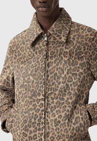 Ζακέτα με σχέδιο λεοπάρ σε απαλό ύφασμα, με γιακά, φερμουάρ μπροστά, δύο πλαϊνές τσέπες και υφασμάτινη υφή.
