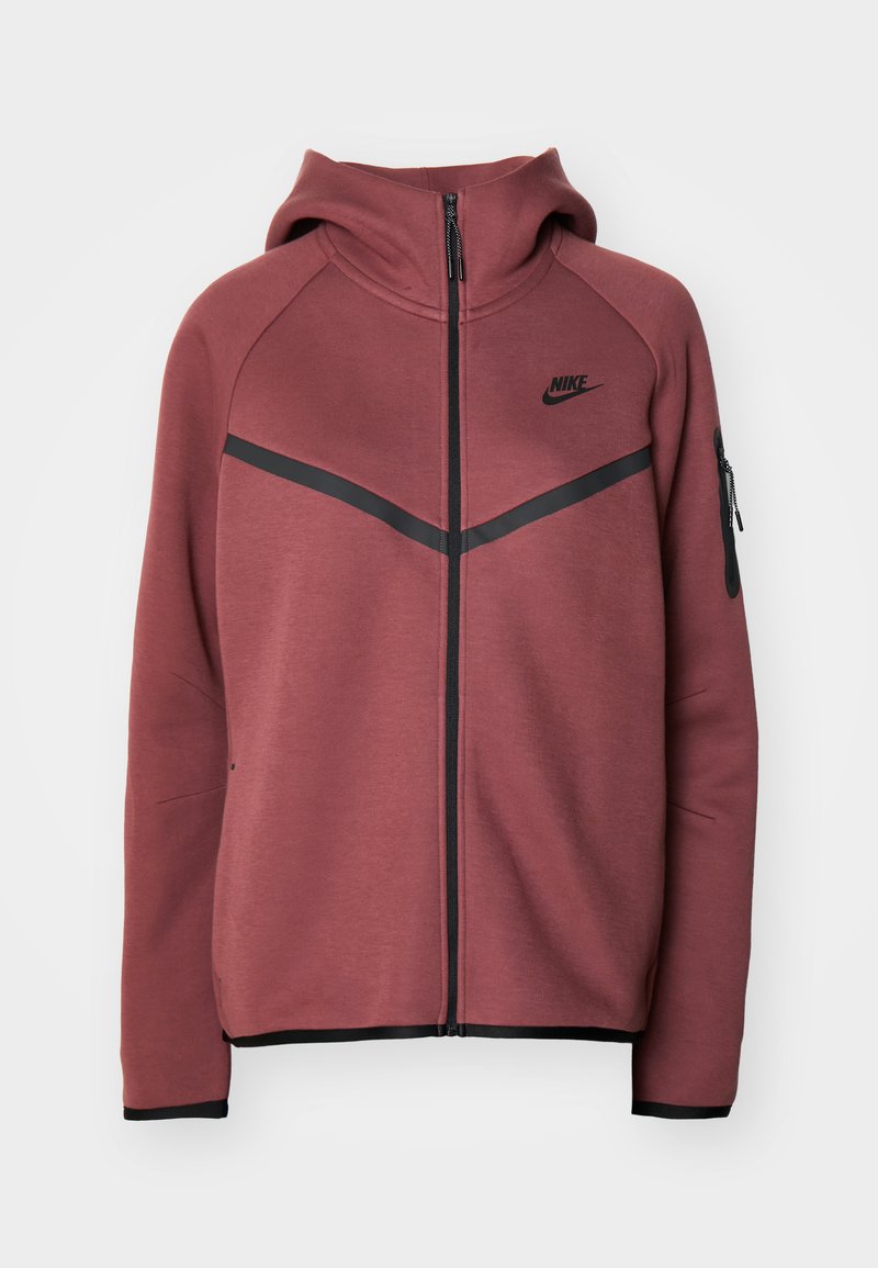 Sudadera de color burdeos con cierre de cremallera, capucha y detalles en negro. Presenta un logo de Nike y un bolsillo lateral con cremallera. Tejido suave con una textura lisa.
