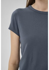 Kurzärmeliges T-Shirt mit Rundhalsausschnitt in einem einfarbigen Dunkelblau. Weicher, glatter Stoff mit minimalen Nähdetails, an den Schultern eng anliegend.