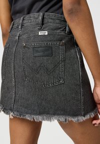 Musthave mustrekkide mini seelik, kus on frayed äär, kaks tagumist taskut ja nahkne logo silt kontrastsete õmblustega.