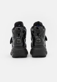 Black patent leather high-top sneakers with Velcro straps, padded collars, chunky black rubber soles, and a circular logo on the heel.