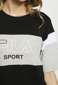Tričko s barevným blokováním v černé, šedé a bílé barvě. Krátké rukávy, kulatý výstřih, s logem "FILA" a textem "SPORT" v kontrastní černé barvě.