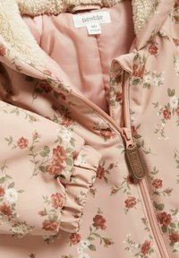 Floral babyjasje in zachtroze, met een pluche binnenvoering, gerimpelde mouwen en een rits met een leren label. Versierd met kleine bloemen.