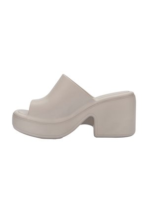 Scarpa in gomma beige con punta aperta, soletta curva e tacco a piattaforma chunky con superficie testurizzata.