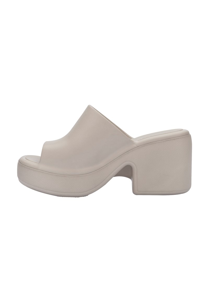 Beżowe gumowe klapki z otwartym palcem, zakrzywioną wkładką i masywnym obcasem z teksturowanej powierzchni.