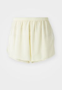 Shorts jaune clair en matériau doux, dotés d'une taille élastique et d'un design ample et fluide avec un ourlet arrondi.