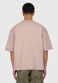 Helles rosa T-Shirt mit kurzen Ärmeln, Rundhalsausschnitt und lockerer Passform. Es hat eine glatte Textur und verstärkte Nähte entlang des Saums und der Ärmel.