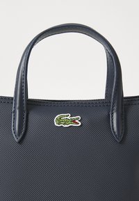 Borsa tote strutturata di colore blu navy con manici lisci, con il logo coccodrillo verde di Lacoste ricamato sulla parte anteriore. Materiale texturizzato.