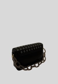 Borsa a mano in pelle nera con parte superiore borchiata e occhielli metallici, chiusura a pattina e tracolla a catena chunky.