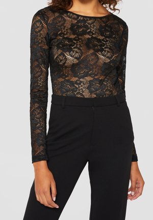 Black lace bodysuit with floral pattern, long sleeves, and a round neckline, paired with high-waisted black trousers.
