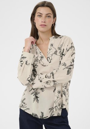 Beige blouse with black botanical print, featuring a notch collar, long sleeves, and a relaxed fit. Made of lightweight fabric.