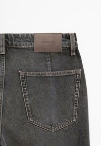 Ciemnoniebieskie dżinsy z skórzaną naszywką z napisem "Massimo Dutti" z tyłu. Posiadają kontrastowe przeszycia oraz klasyczny wzór kieszeni.