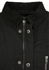Giacca nera con collarino in corduroy, zip frontale e bottoni a pressione. Realizzata in un tessuto testurizzato con dettagli di cucitura.