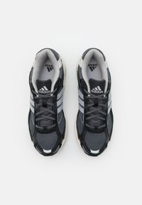 Svarta och grå träningsskor i mesh och syntetiskt material, med tre silverränder, rund tå och framträdande snörningssystem.