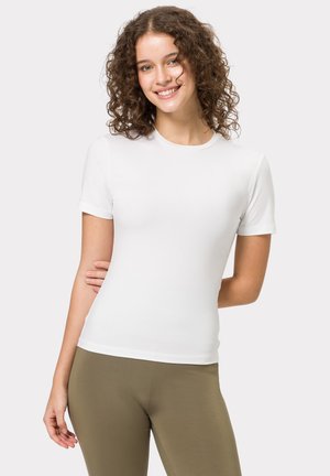 Weißes, kurzes, eng anliegendes T-Shirt aus glattem, dehnbarem Stoff, kombiniert mit olivgrünen Leggings. Einfacher Rundhalsausschnitt.
