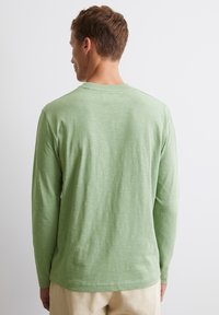 Langärmliges Hemd aus weichem, hellgrünem Stoff mit strukturiertem Finish. Mit Rundhalsausschnitt und geradem Saum.