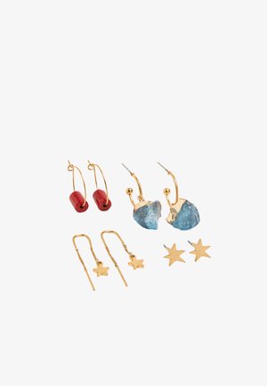 Cztery pary kolczyków w złotym odcieniu: koła z czerwonymi koralikami, koła z niebieskimi kamieniami, delikatne kolczyki na łańcuszku z gwiazdkami oraz złote kolczyki w kształcie gwiazdek.