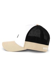 Zwart-wit pet met een beige klep, voorzien van gaaspanelen, een gebogen rand en het "BOSS" logo op de achterkant.