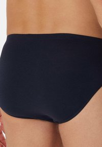 Marineblauwe herenslips van zacht, glad materiaal met een aansluitende pasvorm, voorzien van een lage tailleband en nette randen zonder zichtbare naden.