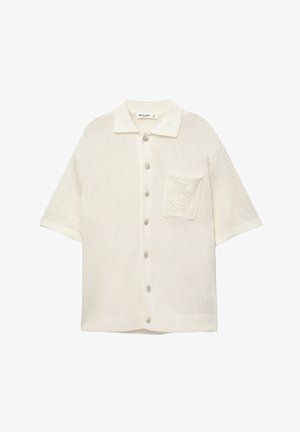 Lyhythihainen, kauluksellinen neuletakki off-white-värisessä kankassa, jossa on teksturoitu kuvio, viisi nappia ja etutasku.