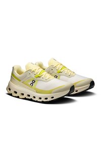 Könnyű futócipők fehér és világos sárga színben, lélegző hálós felsőrésszel, logóval díszítve, vastag talppal és párnázott kialakítással.