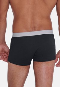 Svarta bomullsboxer med en grå elastisk midja, figurnära design och jämn yta, som visar en ren klippning och minimal detaljering.