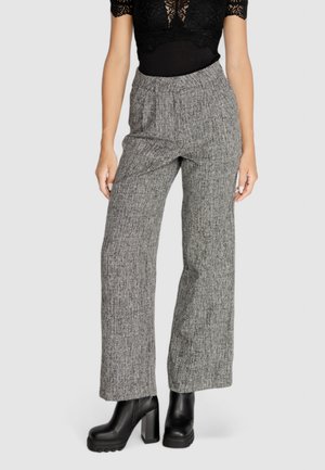 Pantaloni larghi grigi, texture, con vita alta e fascia elastica. Abbinati a stivali platform neri.