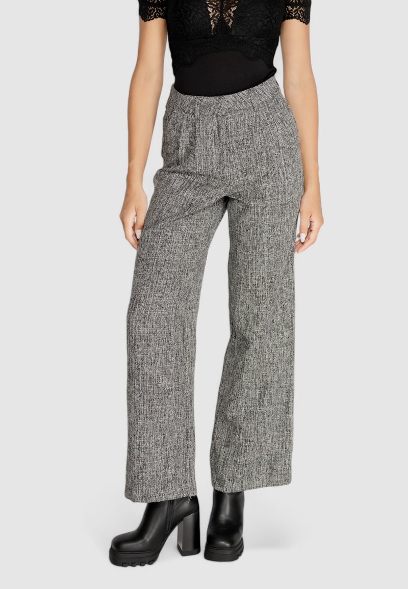 Pantaloni larghi grigi, texture, con vita alta e fascia elastica. Abbinati a stivali platform neri.