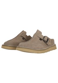 Beige suede slide sandals featuring an adjustable buckle strap, a rounded toe, and a durable rubber sole with textured tread.