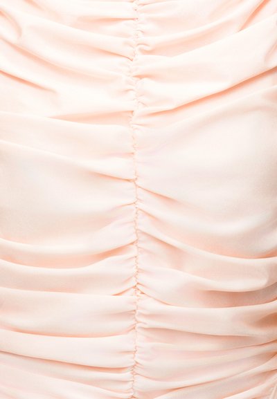 Ανοιχτό ροζ ύφασμα με κάθετο ραμμένο ρουσίνγκ, δημιουργώντας απαλά πτυχώσεις και υφή.