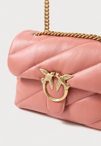 Tűzött rózsaszín bőrtáska arany lánc pánttal és madár alakú fémszegéllyel. Texturált felszín függőleges varrással.