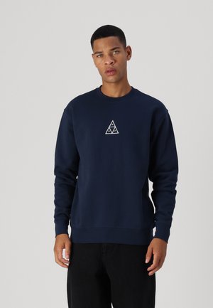 Sudadera de color azul marino en mezcla de algodón, con un logo triangular blanco en el pecho, puños y dobladillo acanalados para una silueta ajustada.