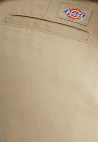 Khaki spodnie robocze z gładkiego, teksturowanego materiału, z tylną kieszenią i naszywką z logo Dickies.