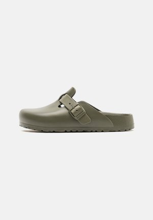 Sabots vert olive en plastique lisse, dotés d'une boucle de sangle ajustable, d'un bout rond et d'une semelle texturée pour une meilleure adhérence.