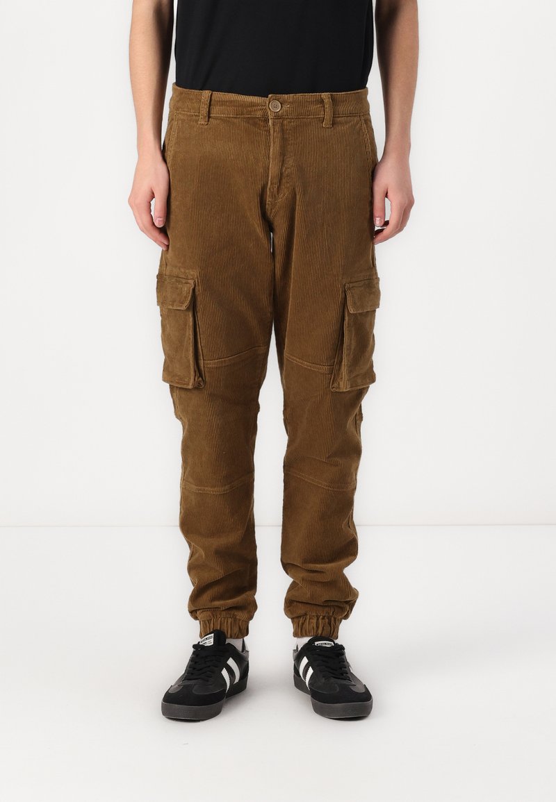 Braune Corduroy-Cargo-Hosen mit elastischen Bündchen, mehreren Seitentaschen, einem Knopfverschluss und einem geraden Bein-Design. Getragen mit schwarzen Sneakers.