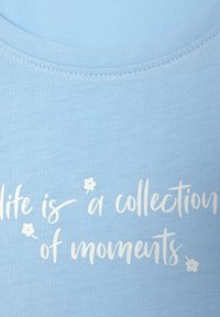 Light blue t-shirt with a round neckline featuring white text that reads, "life is a collection of moments," with small floral accents.