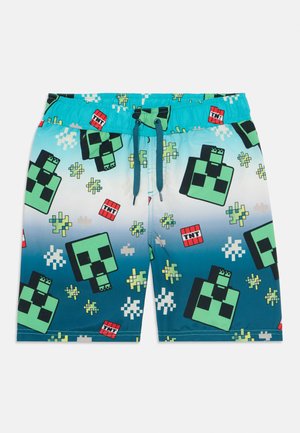 Calções de banho com um degradê que vai do azul claro ao azul escuro, adornados com designs de personagens em pixel verde e blocos de TNT vermelhos. Cintura elástica com cordão.