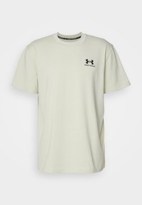 Ljusbeige bomulls t-shirt med korta ärmar, rund krage och svart Under Armour-logotyp på vänster bröst.