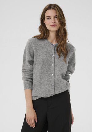 Gray wool cardigan with a round neckline, six purple buttons, ribbed cuffs, and a relaxed fit. Worn over black trousers.