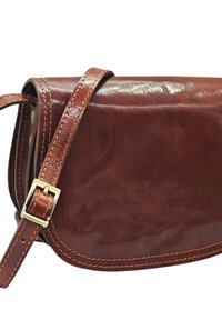 Sac à épaule en cuir marron avec une finition lisse, une forme courbée et des coutures contrastées. Il dispose d'une boucle en métal et d'une bandoulière réglable.