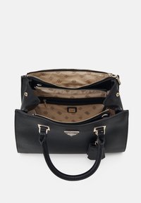 Sort læderhåndtaske med en tekstureret overflade, guldfarvet hardware og et mønstret beige indre. Har flere rum og en aftagelig rem.