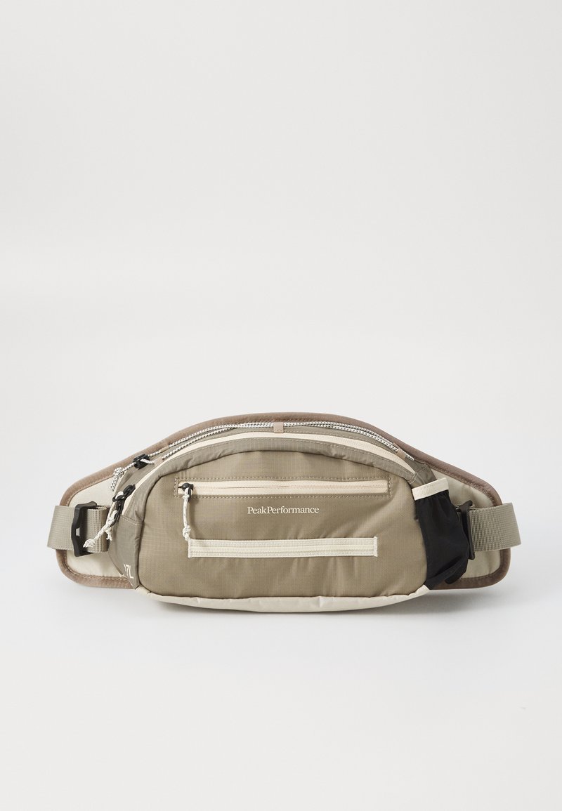 Borsa a vita beige realizzata in tessuto texturizzato, caratterizzata da più scomparti con zip, una tracolla regolabile e un logo sul davanti.