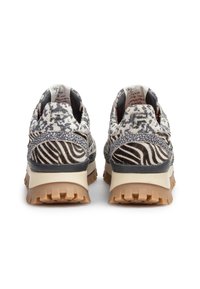 Vista posteriore di scarpe da ginnastica con tomaia a motivi misti che presentano design a zebra e astratti, in colori grigio e bianco, e una suola robusta color tan.