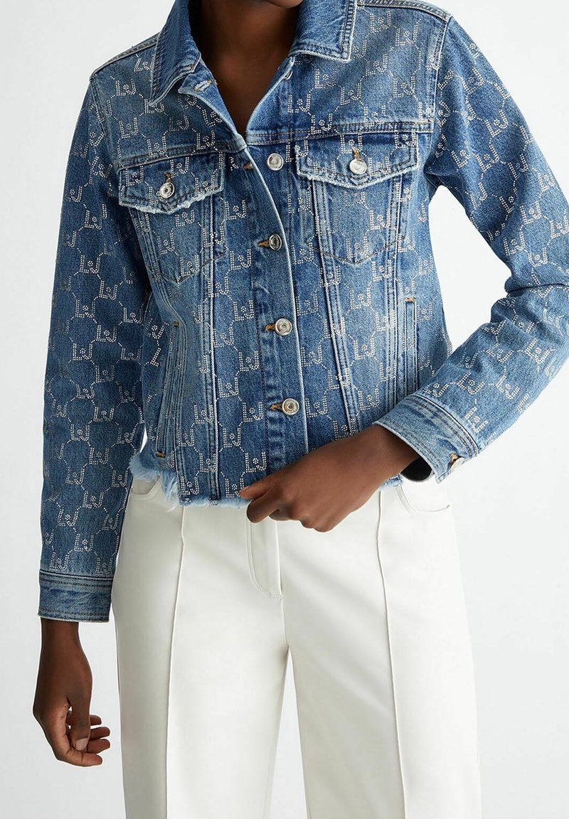 Jeansjacka i ljusblå färg med subtilt logomönster, klassisk krage, bröstfickor, knappstängning och fransad fåll.